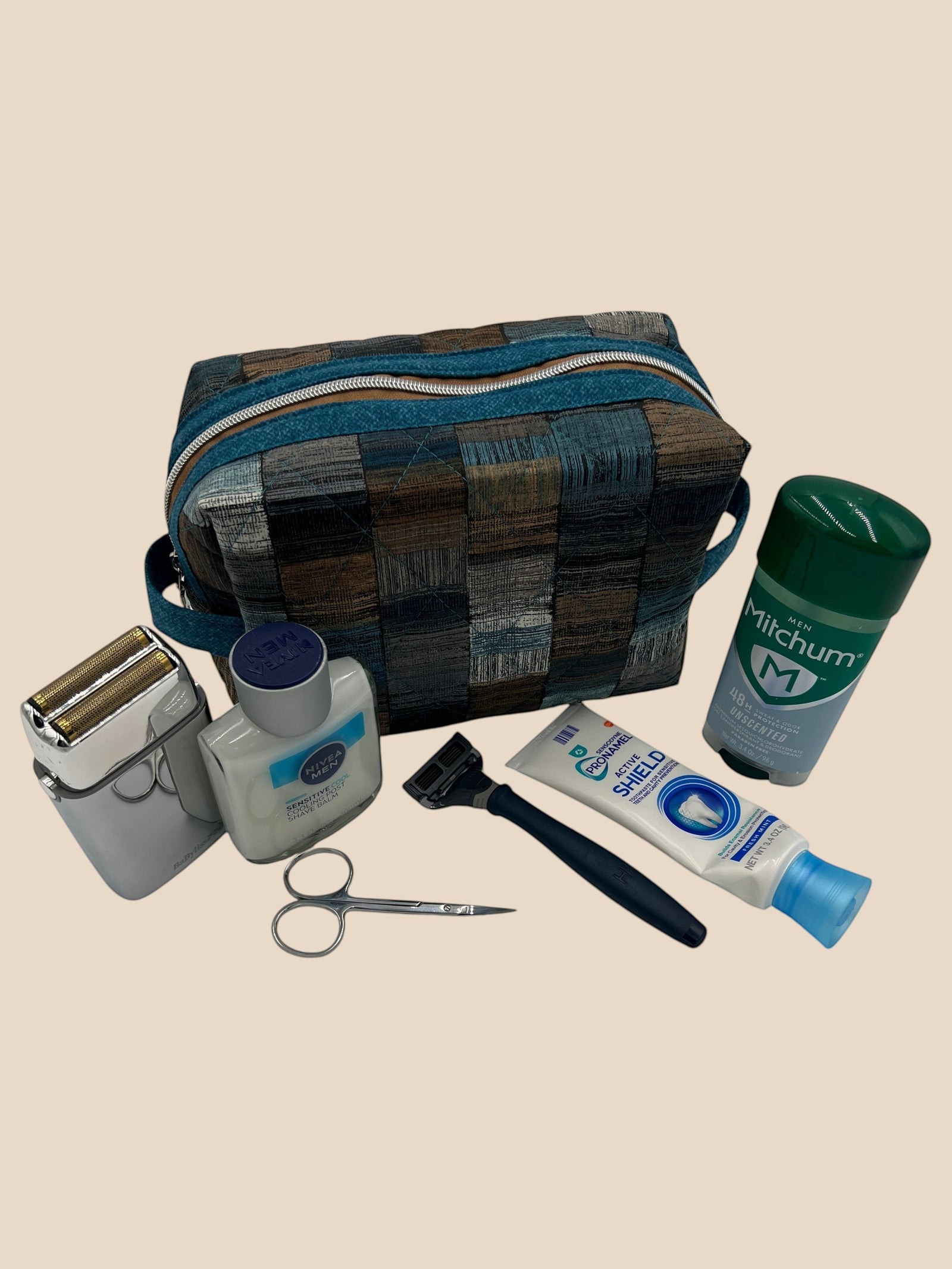Blue and Earth Tone Patchwork Holland pouch styled beside toiletries — shaver, lotion, razor, and travel items — handmade by The Cozy Daisy