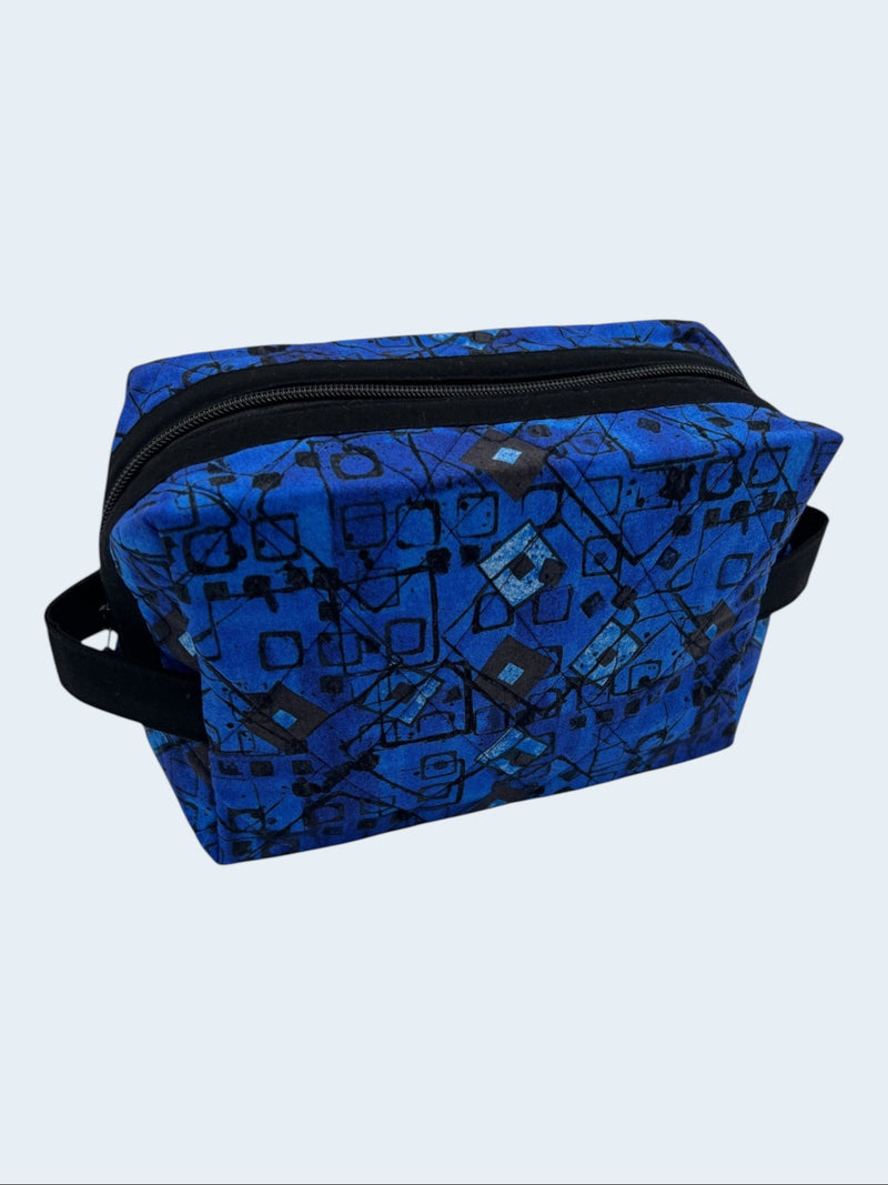 Blue Geometric Holland pouch in a bright blue and black print, front three-quarter view, zipped closed — handmade by The Cozy Daisy