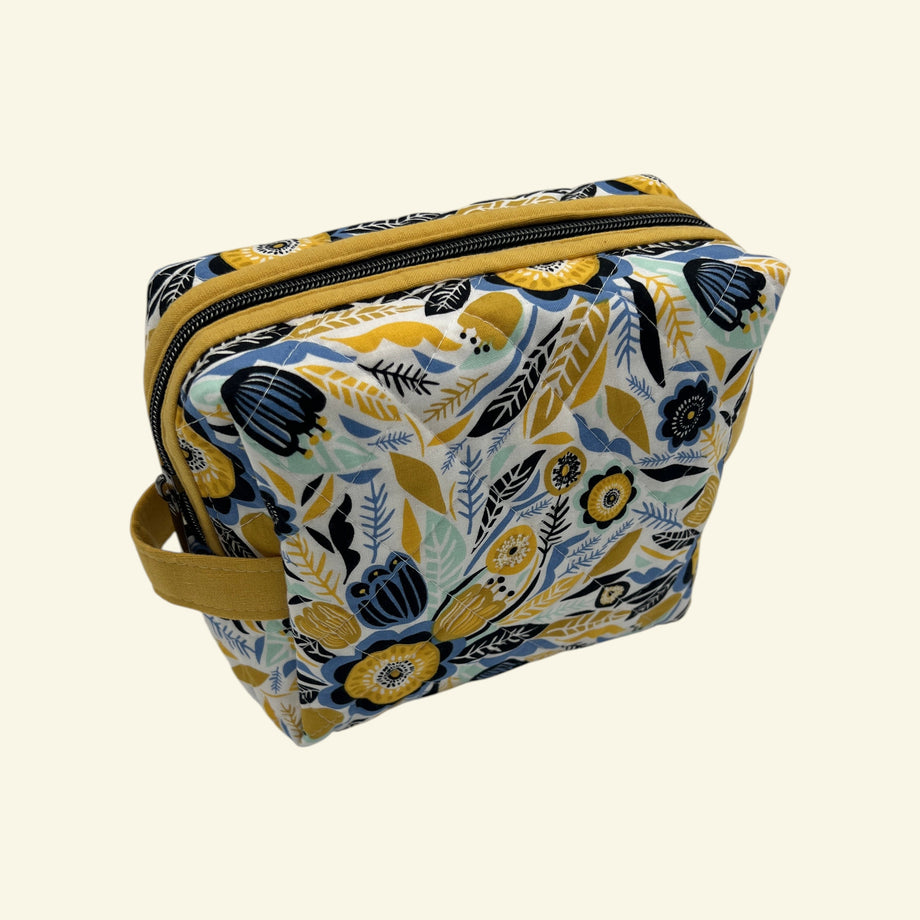 Blue and Gold Wildflower Holland pouch in a cheerful floral print, front three-quarter view, zipped closed — handmade by The Cozy Daisy