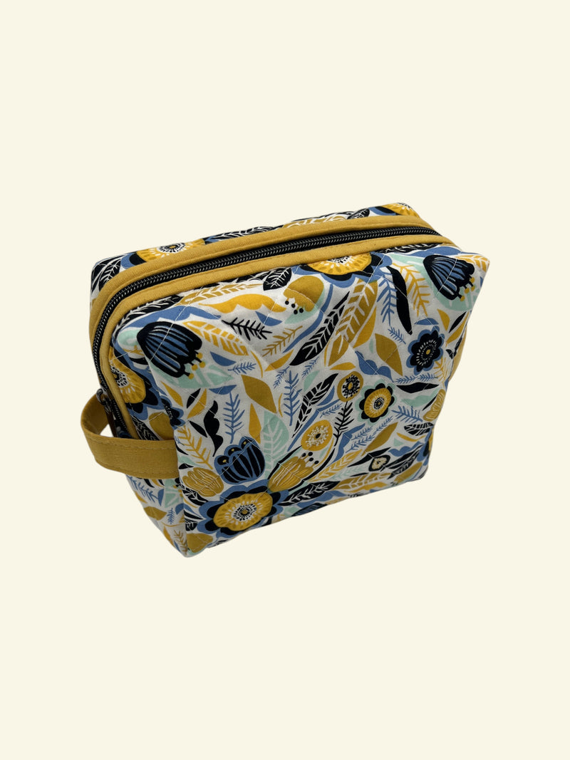 Blue and Gold Wildflower Holland pouch in a cheerful floral print, front three-quarter view, zipped closed — handmade by The Cozy Daisy
