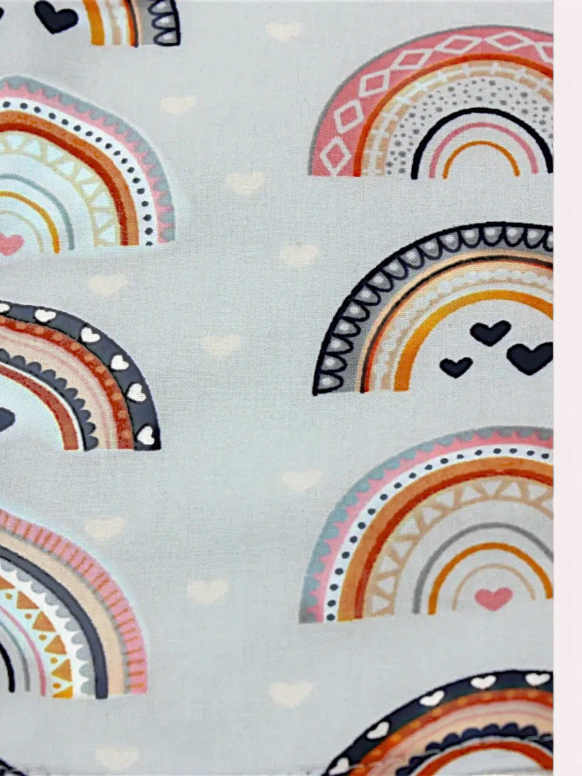 The Cozy Daisy bib and burp cloth set featuring a blue rainbow print with navy and terracotta arches on cotton.