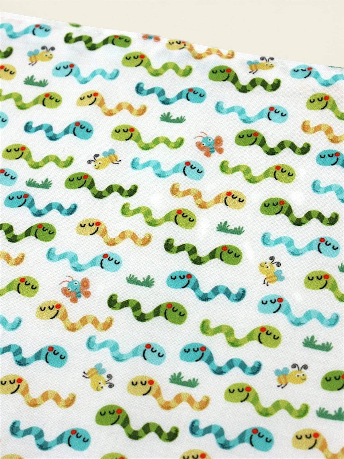 The Cozy Daisy baby bib featuring a playful worms and insects print on soft white cotton fabric.